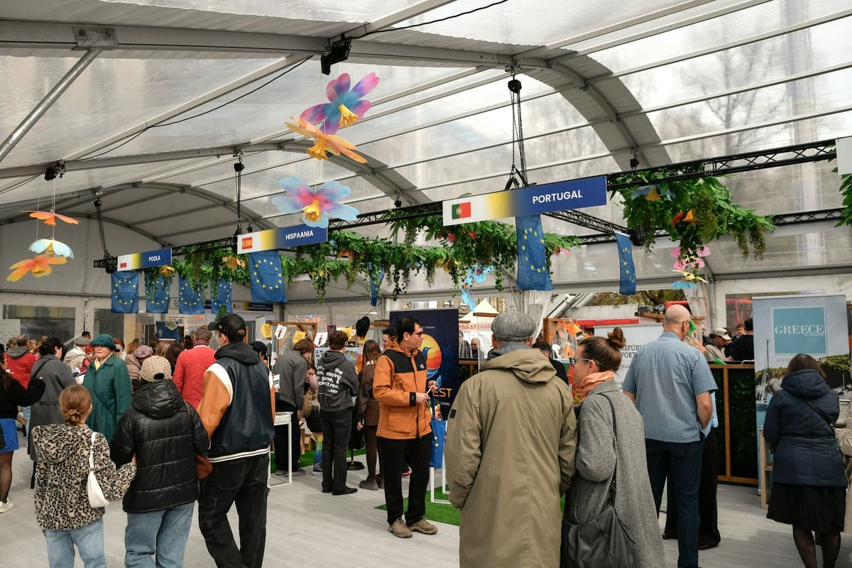 Visitors walking the central aisle of a trade fair between exhibitor stands.